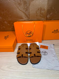 Hermes slide sandals with H-style cutout straps, tan-brown leather, flat sole