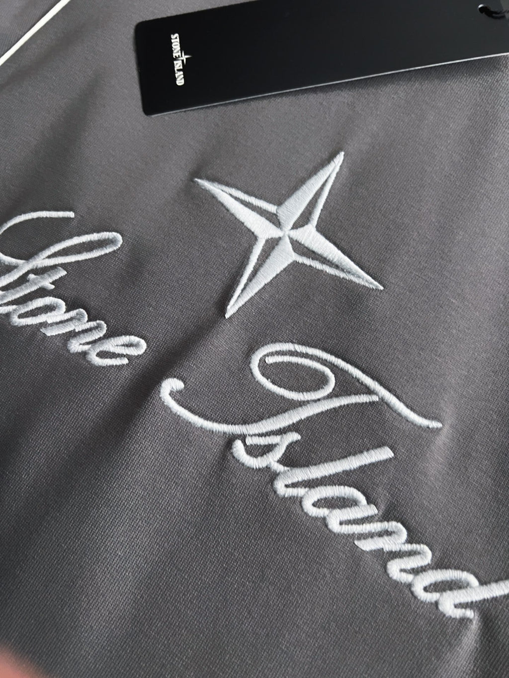 Stone Island T-shirt fabric with white star logo and cursive script embroidery