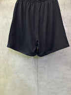 Black drawstring shorts with elastic waistband and tapered back hem