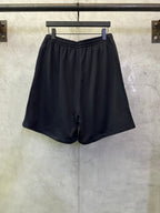Black drawstring shorts with elastic waistband, center seam, and Balenciaga side mark