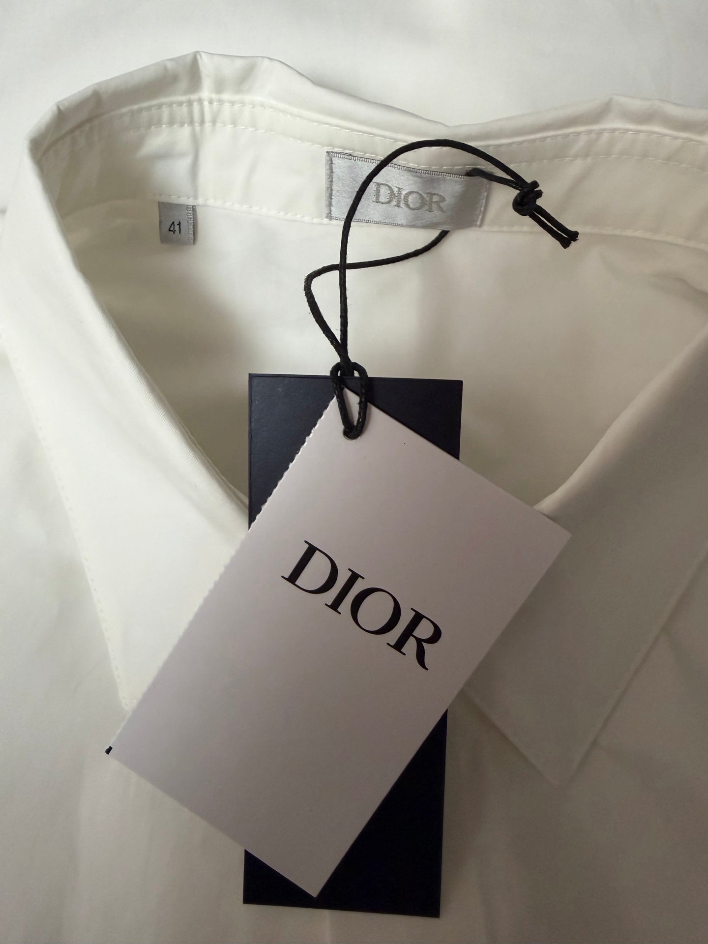 White short-sleeve shirt with size label and Dior-branded hang tag