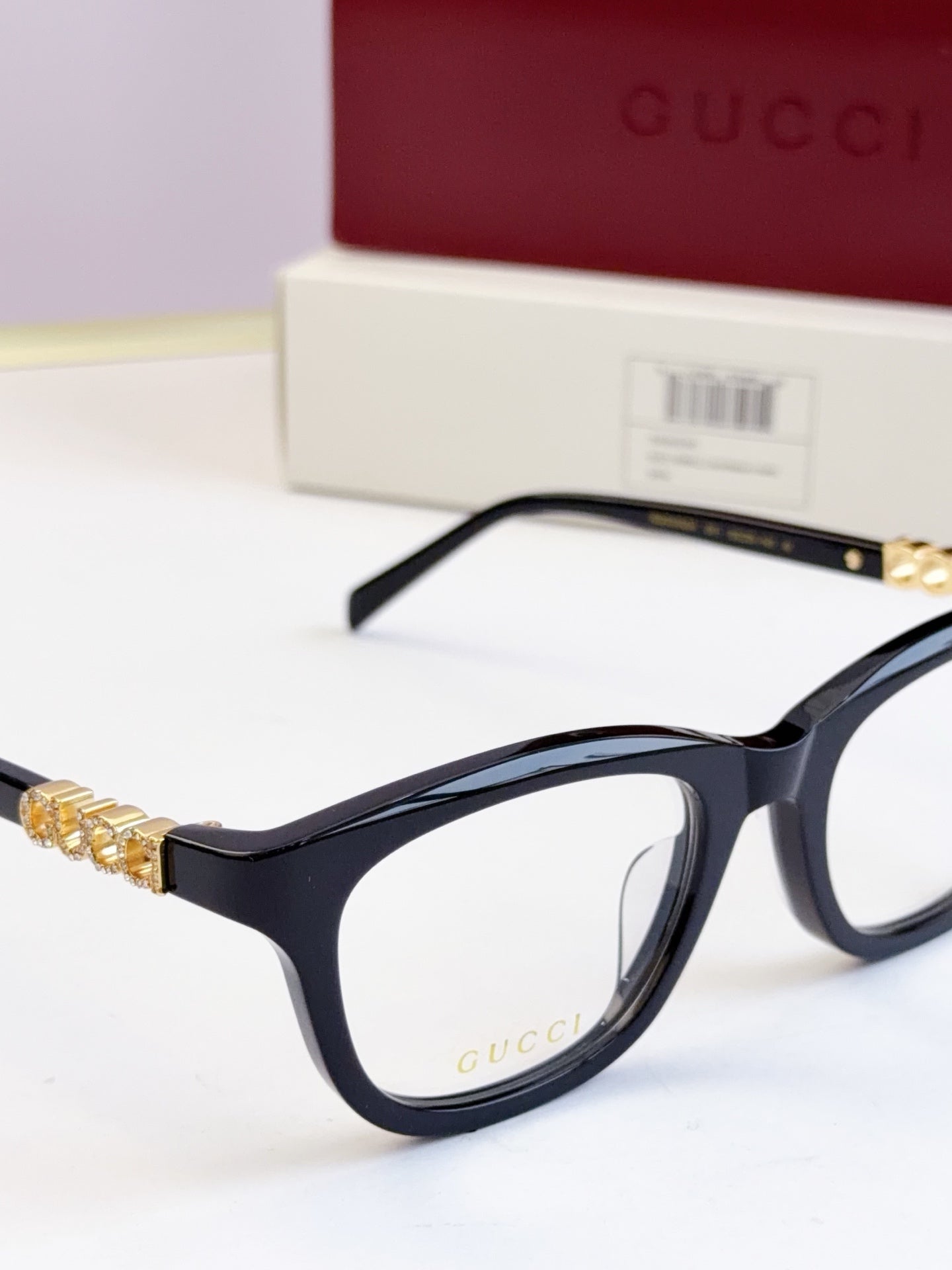 Gucci eyeglasses close-up: black frames with gold chain detail on the temple