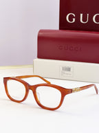 Gucci eyeglasses with amber frames and gold chain detail at the temples