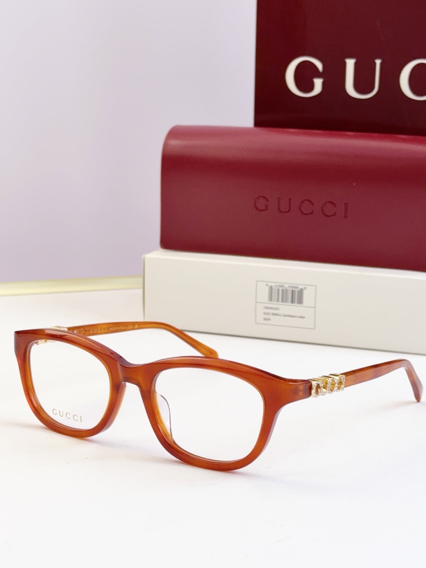 Gucci eyeglasses with amber frames and gold chain detail at the temples