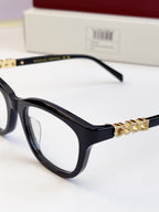 Gucci eyeglasses close-up: black frames with gold chain detail across the front
