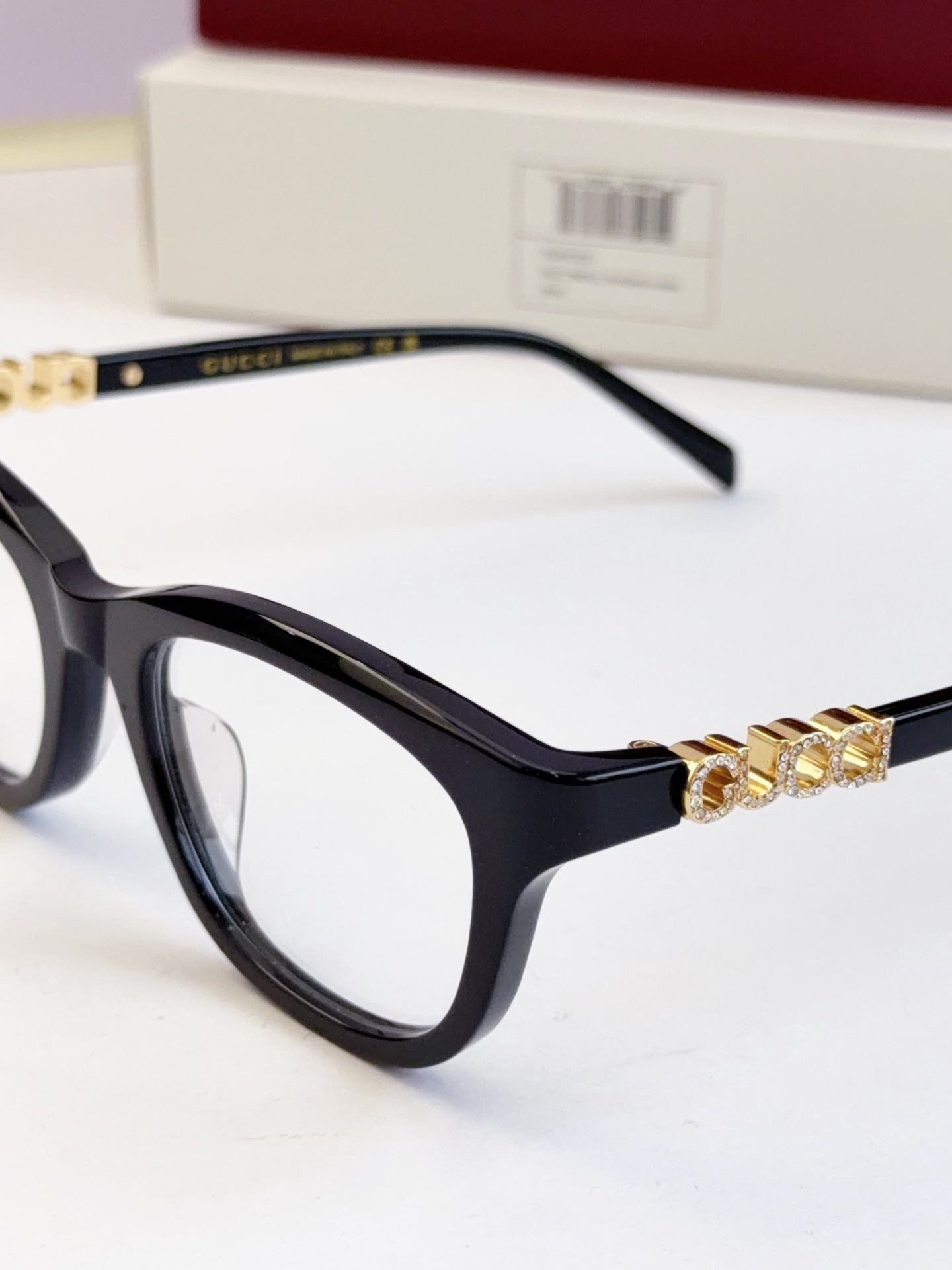 Gucci eyeglasses close-up: black frames with gold chain detail across the front