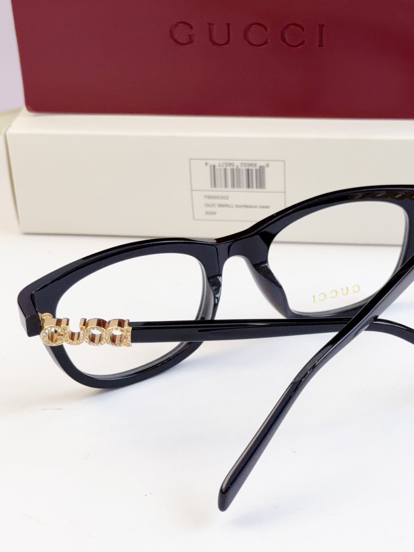 Gucci eyeglasses with black frames and gold chain detail at the bridge