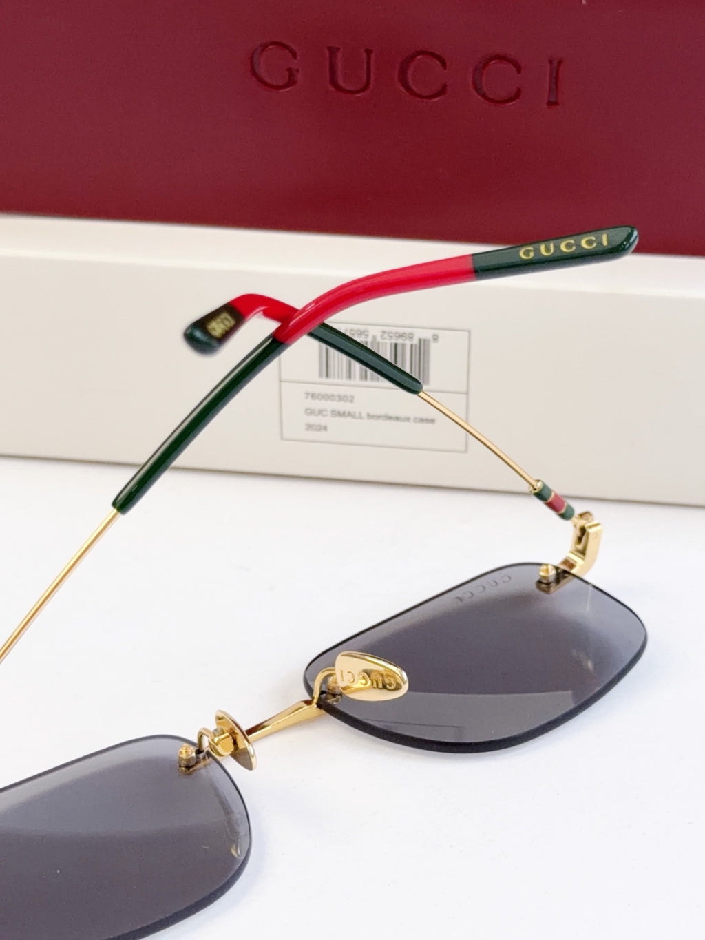 Sunglasses side view, red and green temple arms with gold-tone frame and dark lenses
