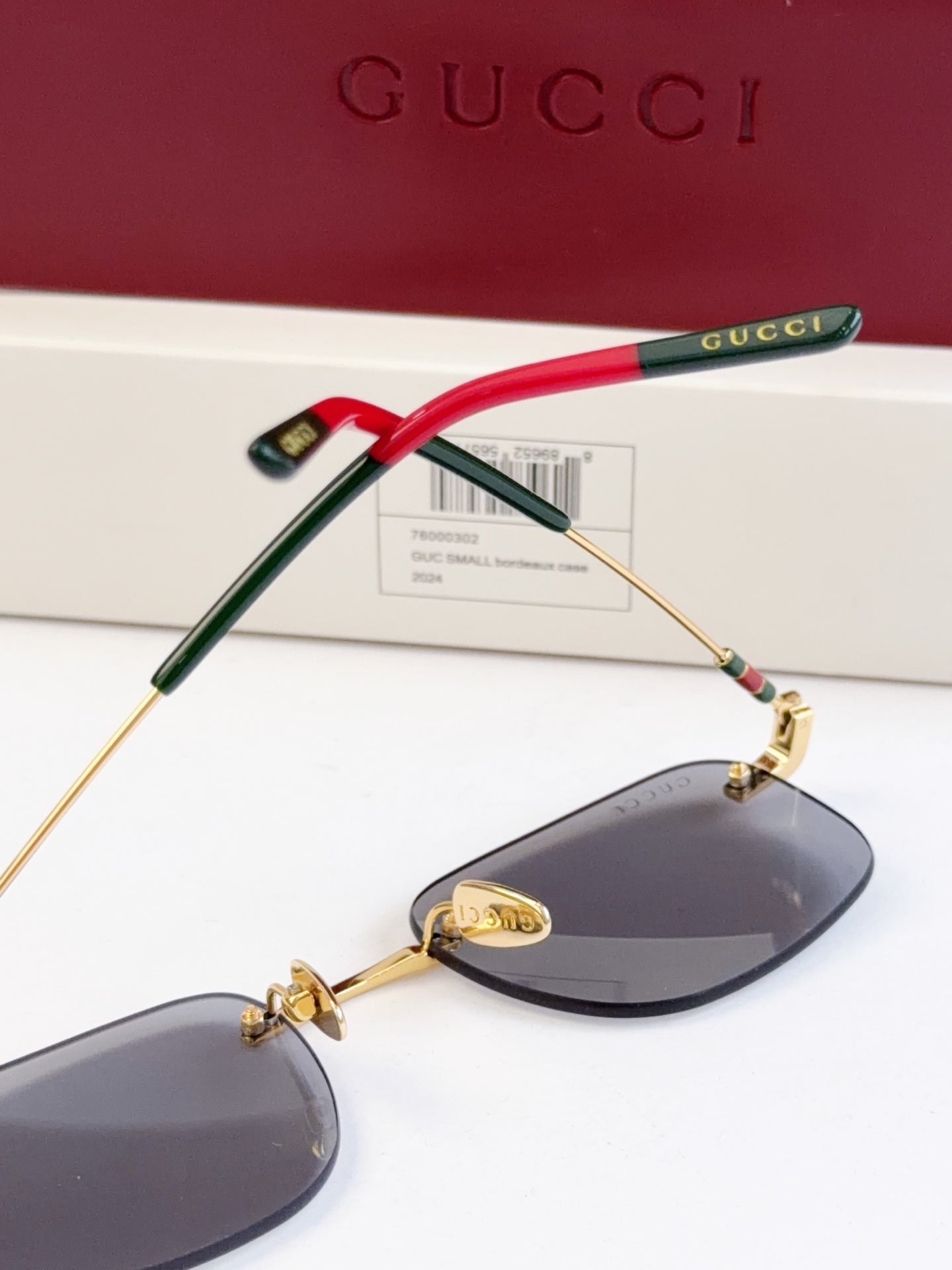 Sunglasses side view, red and green temple arms with gold-tone frame and dark lenses