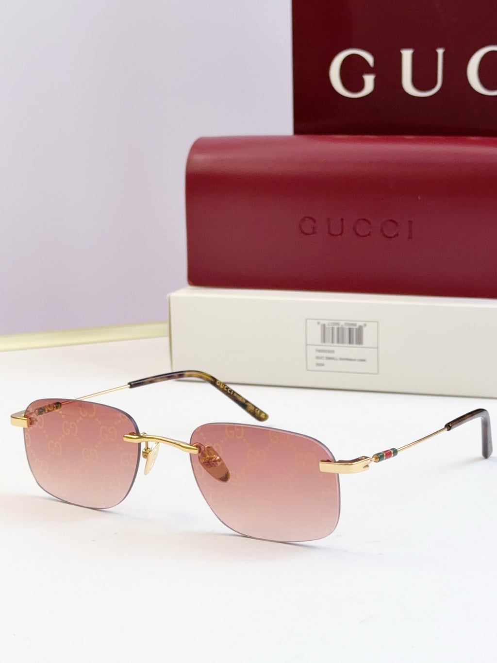 Sunglasses with gold-tone frame and pink-tinted lenses, slim temples