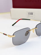 Sunglasses close-up, gold-tone frame with dark blue lenses and green-red temple trim