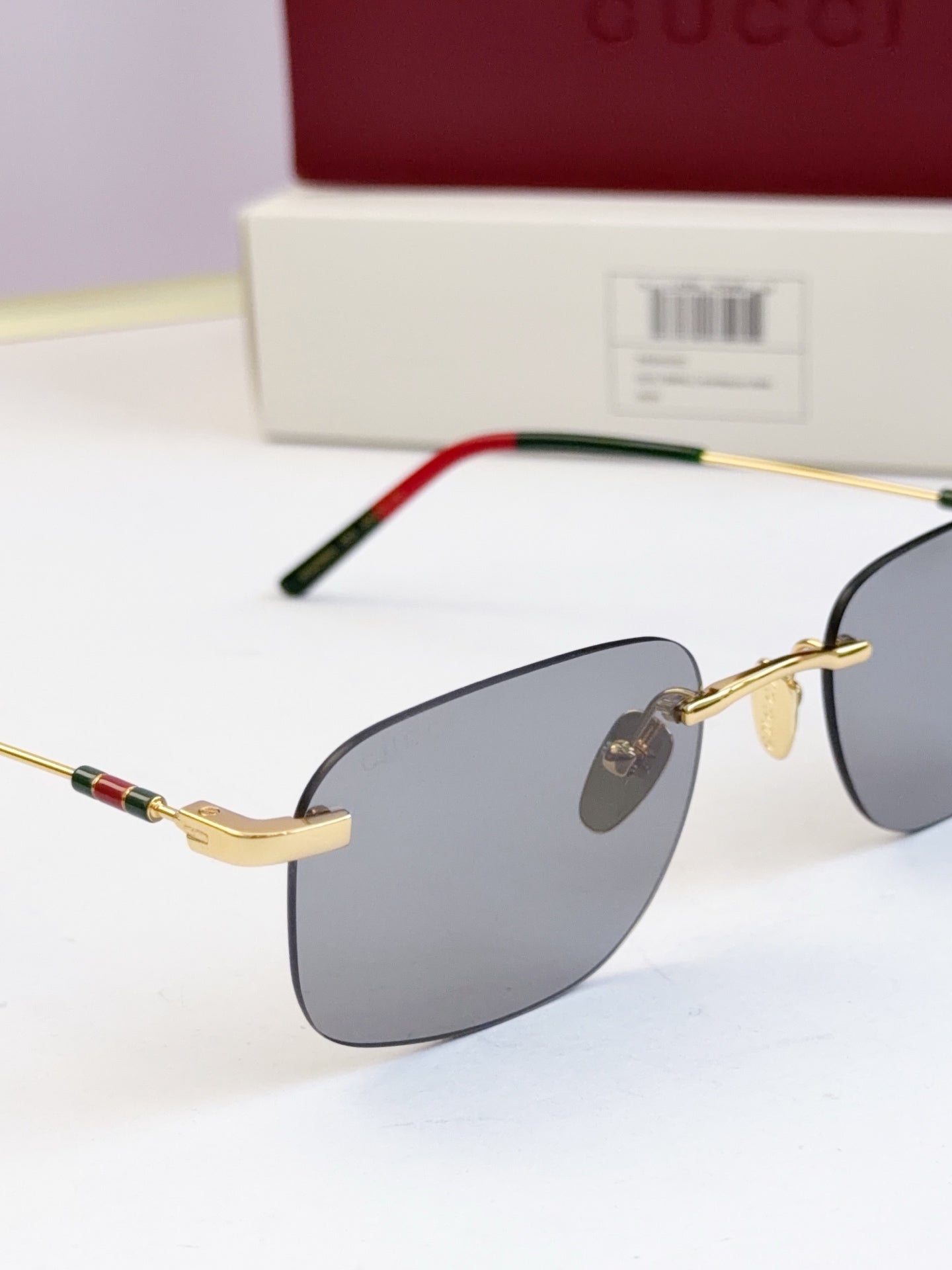 Sunglasses close-up, gold-tone frame with dark blue lenses and green-red temple trim