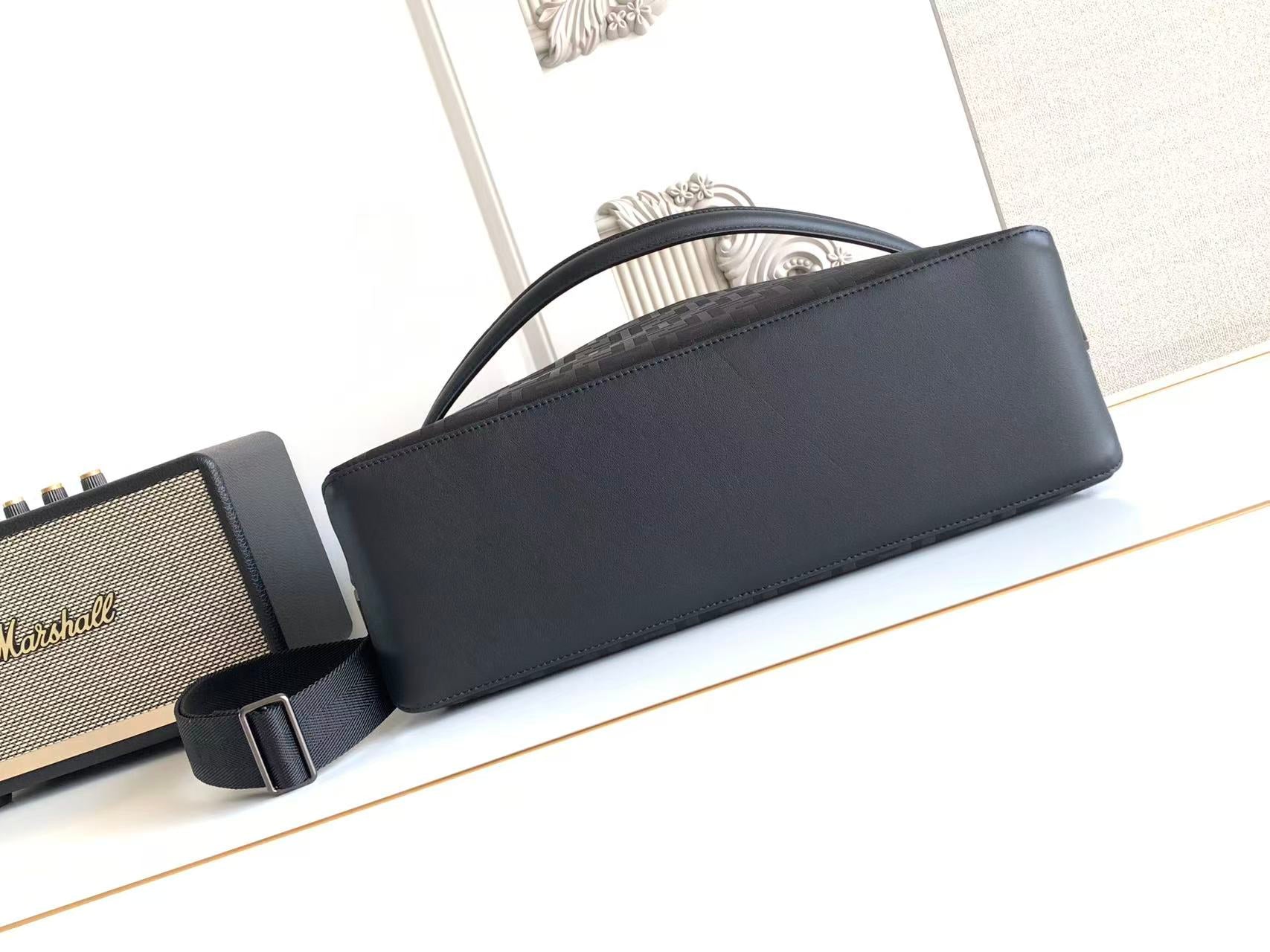 Dark leather baguette bag with top handle and adjustable crossbody strap