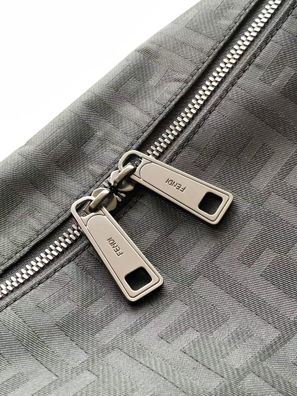 Fendi logo fabric bag close-up with double zippers and metal pull tabs