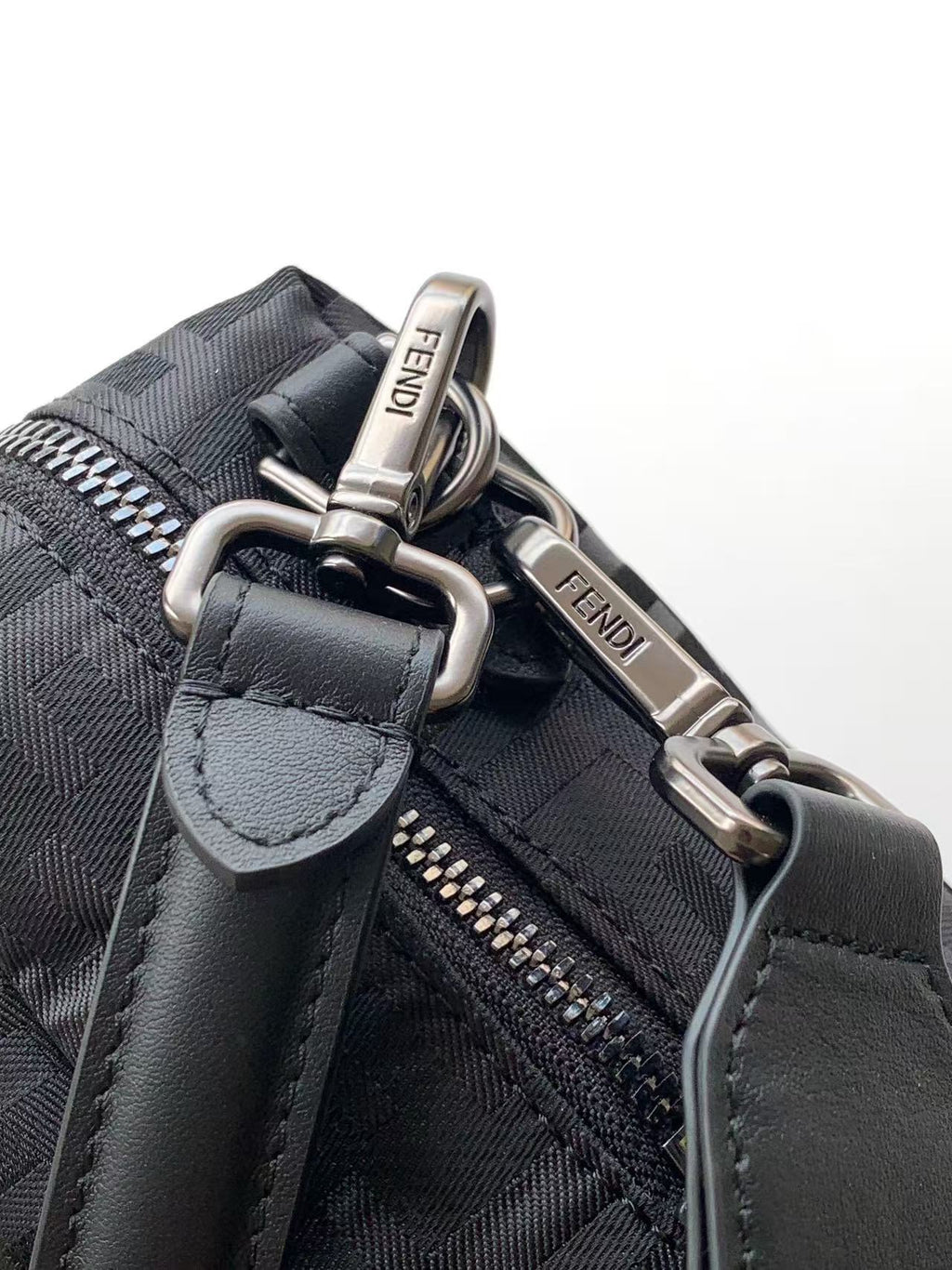 Fendi bag close-up of strap hardware and zipper pull, gray fabric with logo