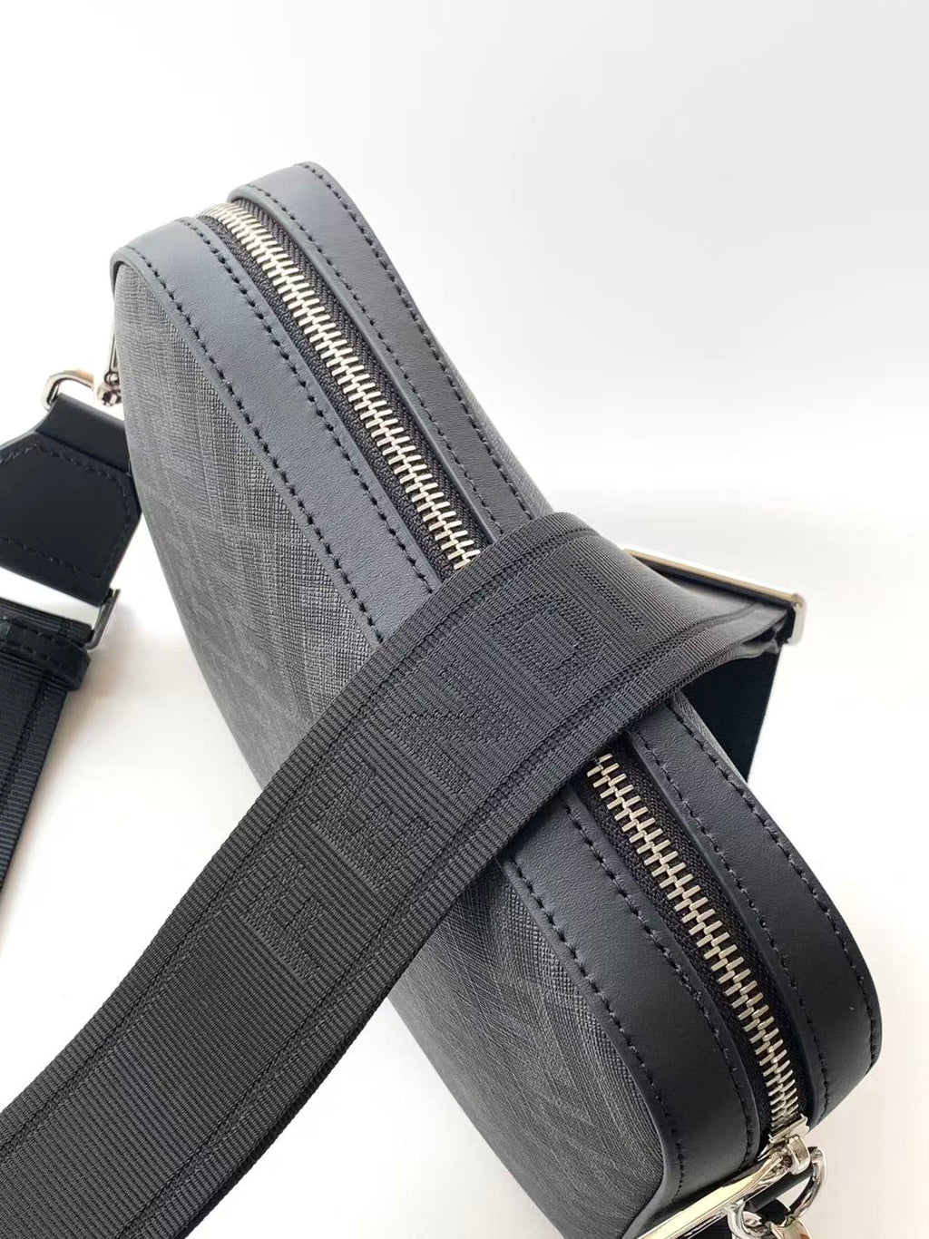 Dark logo crossbody bag with gold-toned zipper and crossbody strap.