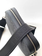 Dark logo crossbody bag with gold-toned zipper and crossbody strap.