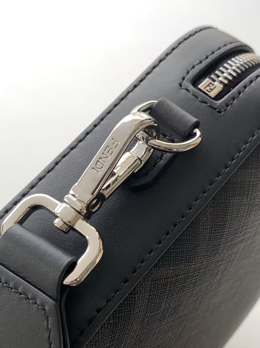 Fendi bag detail: silver clasp and zipper on dark leather with stitched edges.