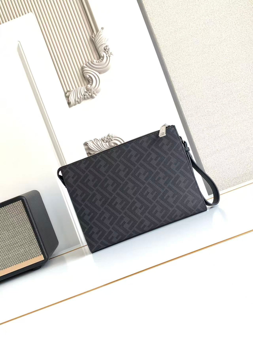 Fendi bag with dark FF monogram front and top handle strap, secured by zipper.