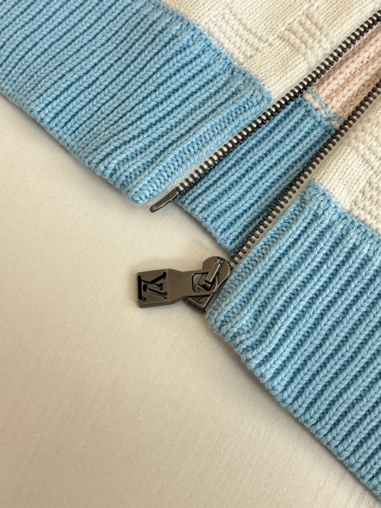 Louis Vuitton zipper pull on light blue ribbed knit hem over cream fabric