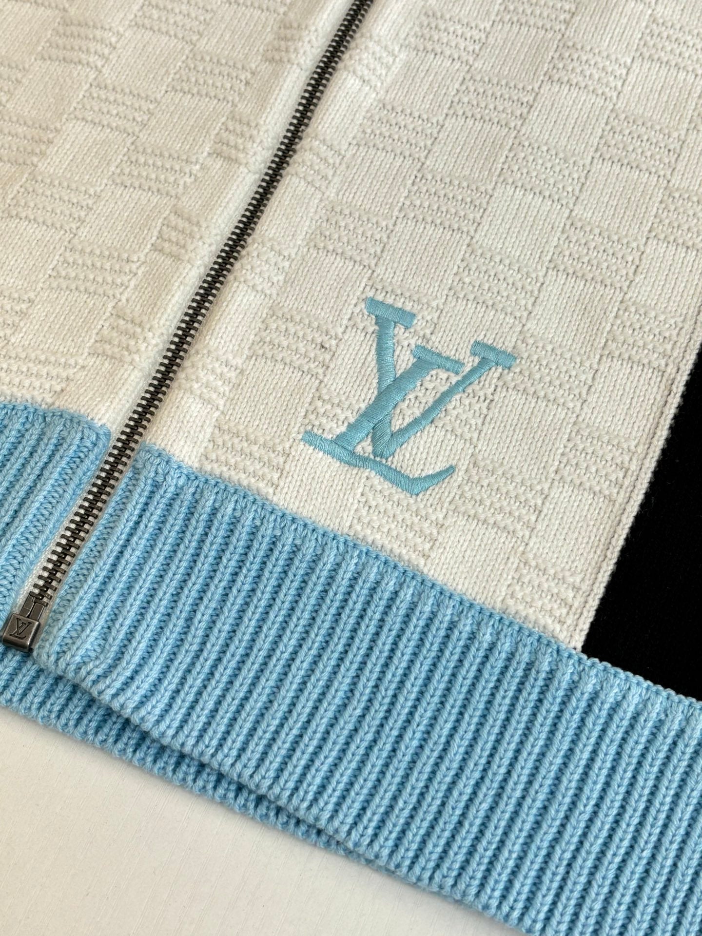 Louis Vuitton knit sweater chest shows light blue LV monogram on cream background