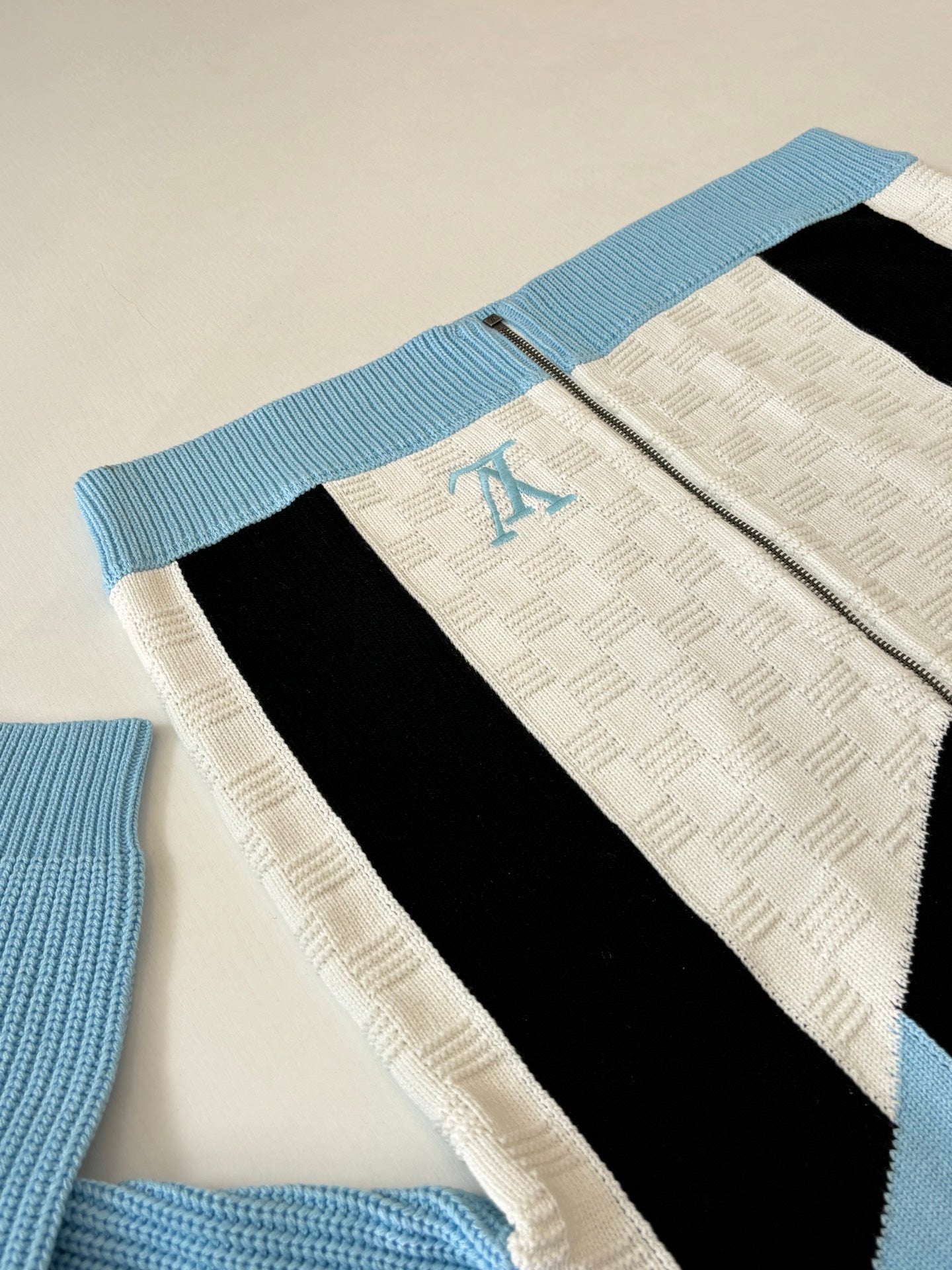 Louis Vuitton knit zip sweater close-up with light blue ribbed hem and black stripe