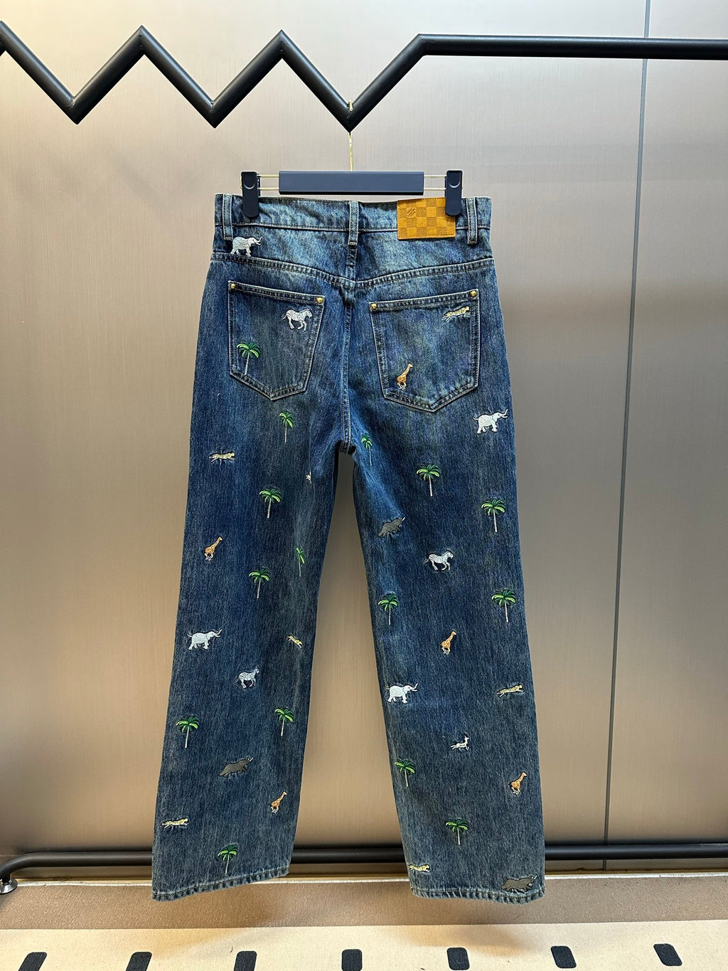 Blue denim pants with animal and palm tree embroidery, back view