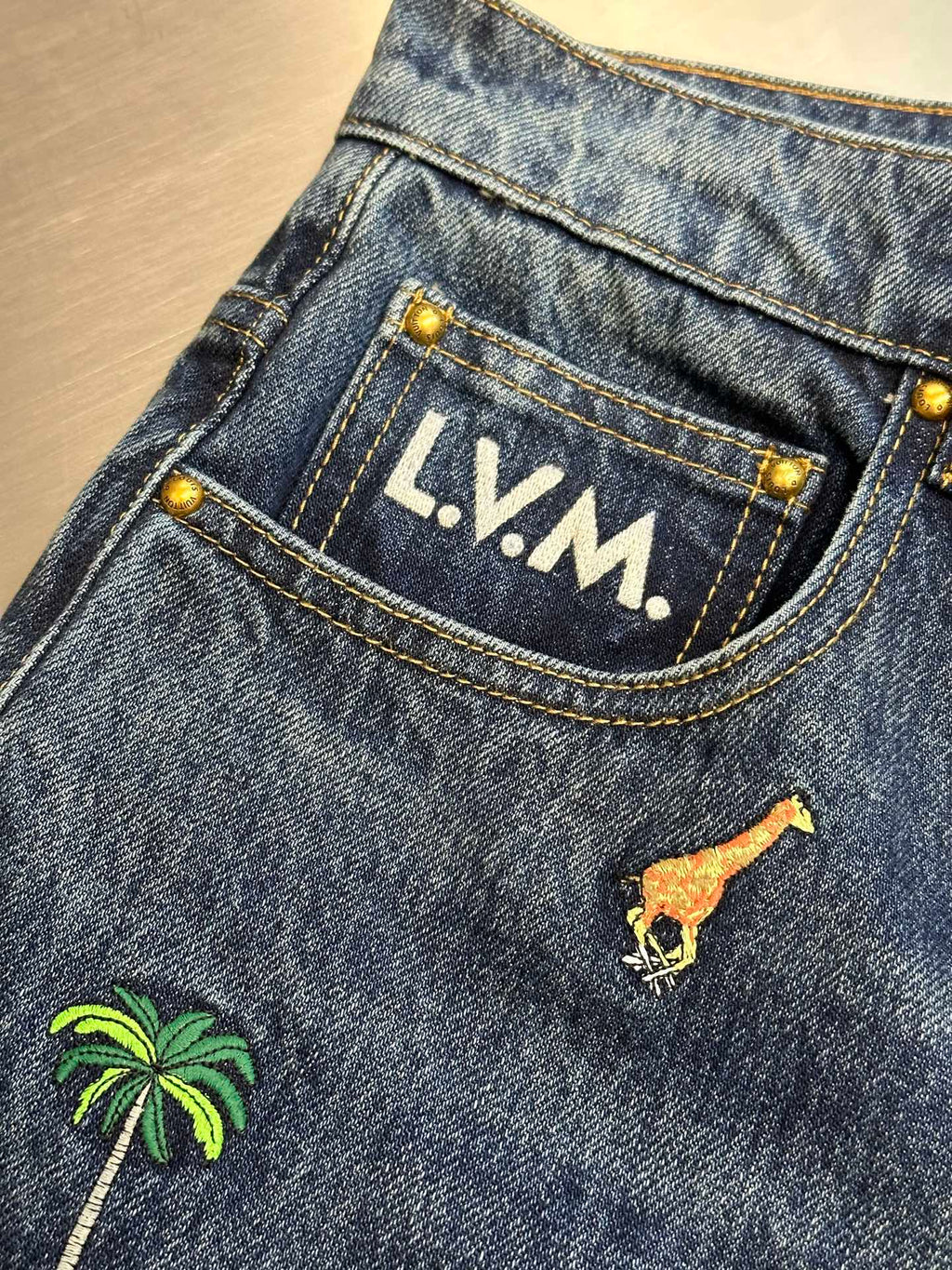 Blue denim jeans with LV.M. patch on waistband and giraffe graphic
