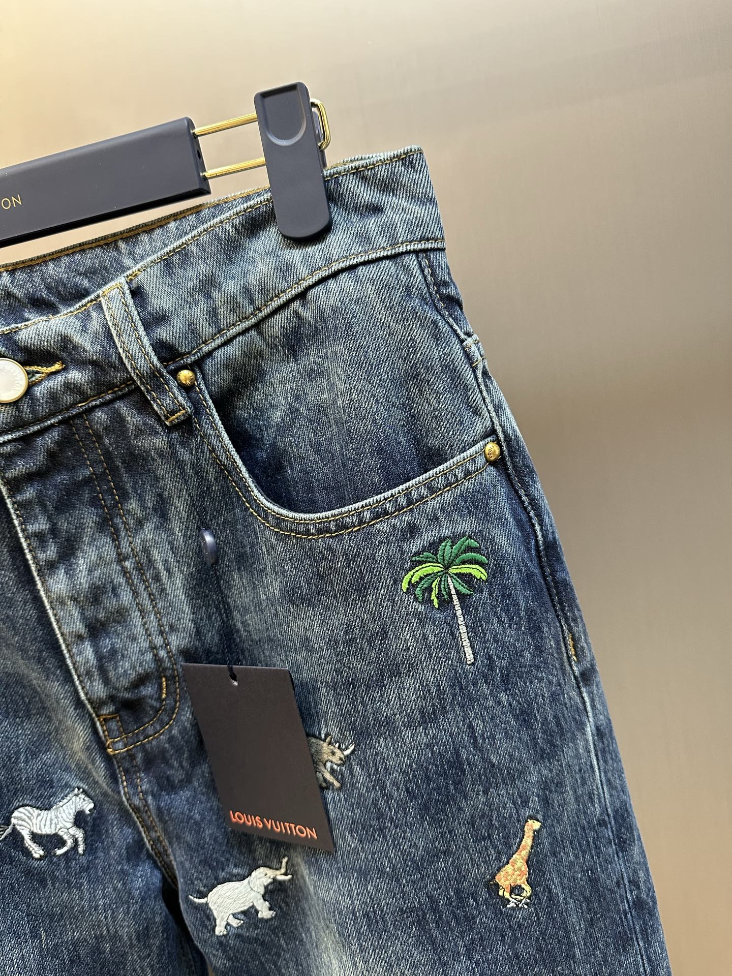 Blue denim jeans with zip fly, front pocket, and palm tree print