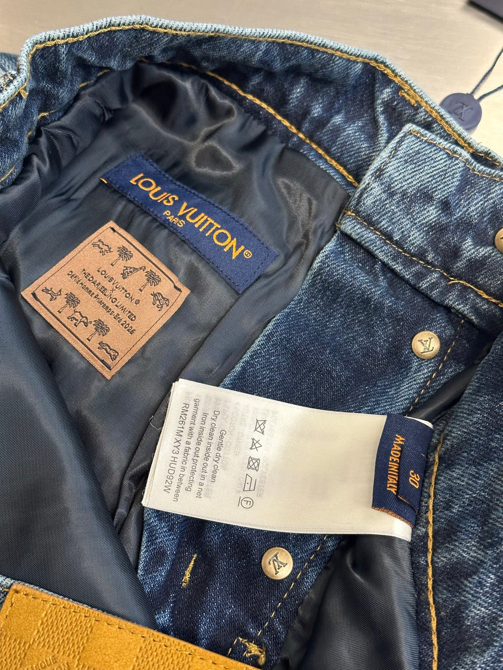 Blue denim pants with interior tag and patch labels, partially open