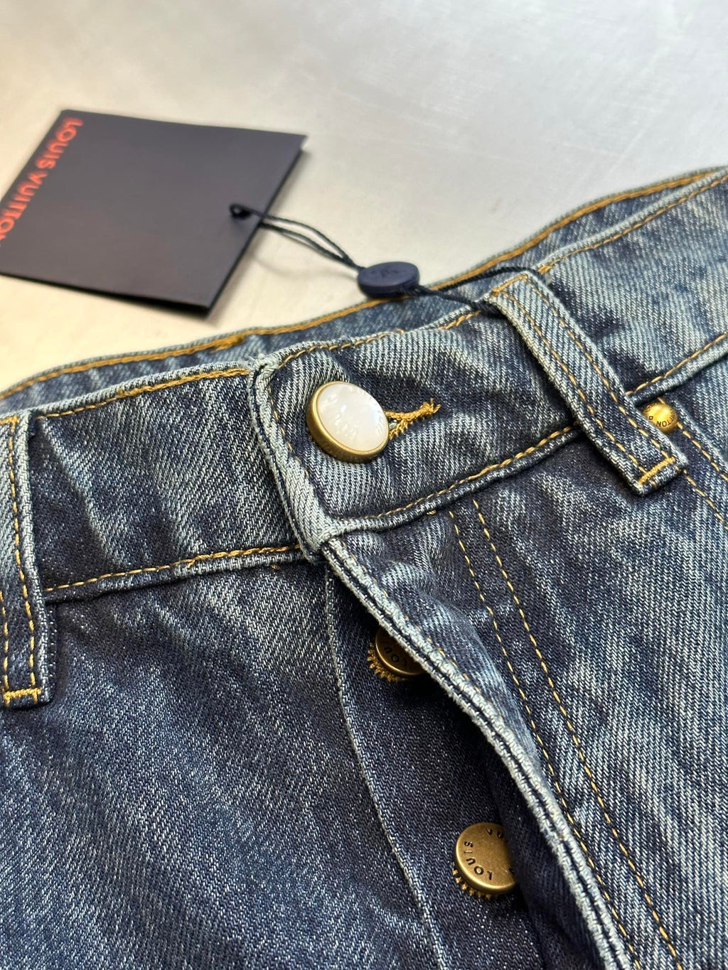 Blue denim jeans with button closure and coin pocket, gold stitching