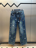 Blue denim pants with scattered animal and palm tree patches, front view