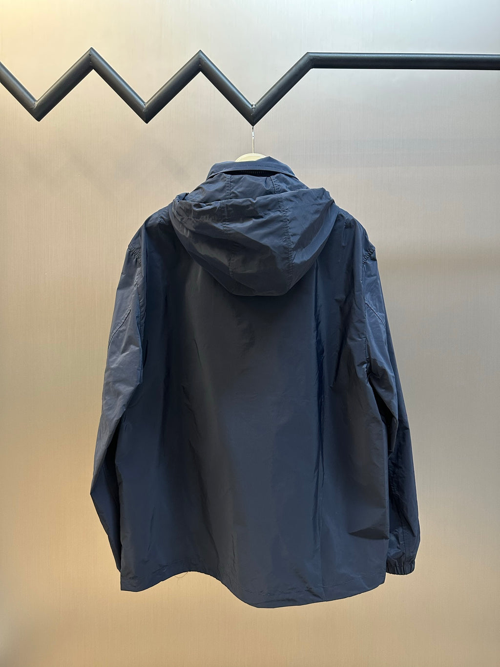 Back view: navy hooded zip jacket with loose fit and long sleeves