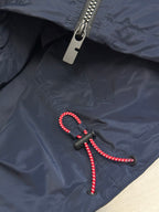 Navy jacket with metal zipper and black pull tab with red beaded cord