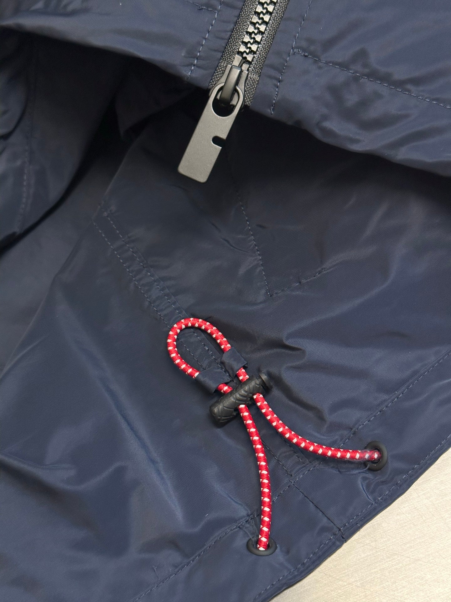 Navy jacket with metal zipper and black pull tab with red beaded cord
