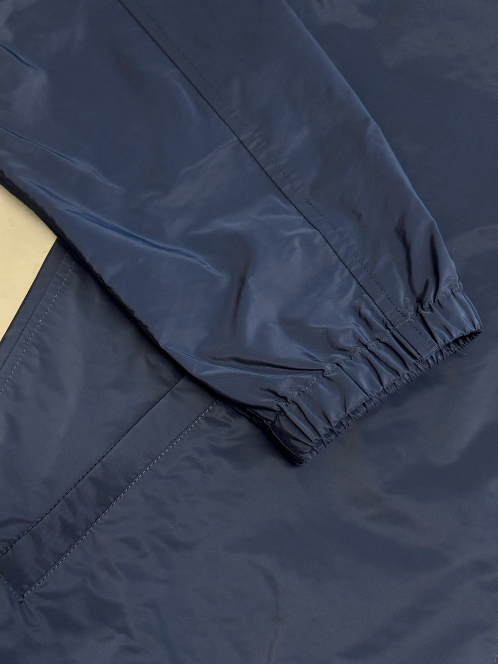 Navy jacket sleeve cuff with elastic hem and visible seam stitching