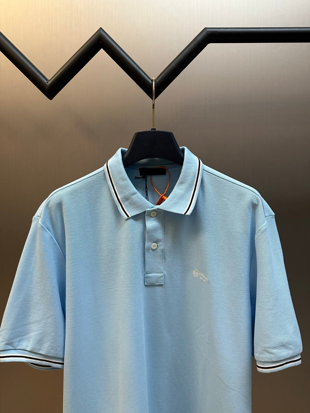 Prada light blue polo shirt with open collar and striped trim on cuffs