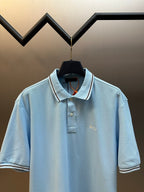 Prada light blue polo shirt with open collar and striped trim on cuffs