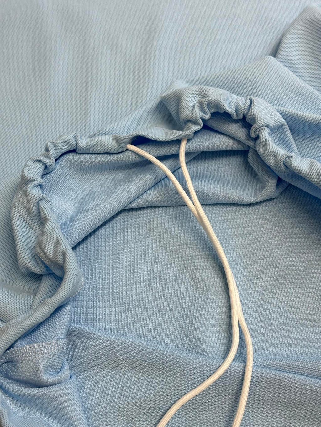 Prada light blue polo shirt with drawstring cords on folded fabric