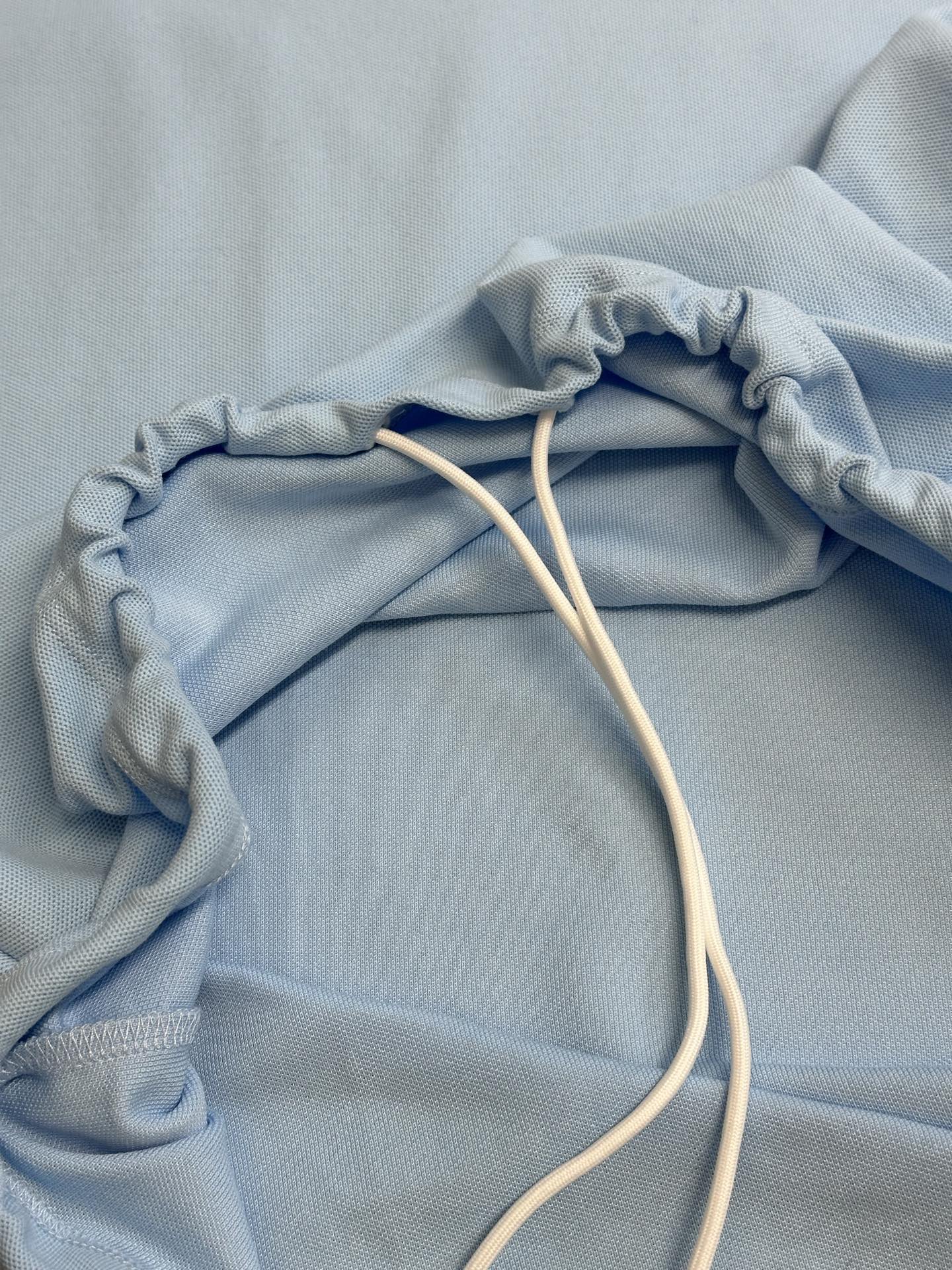 Prada light blue polo shirt with drawstring cords on folded fabric
