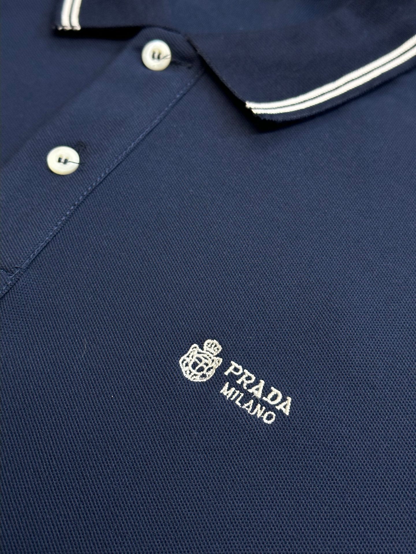 Navy Prada polo shirt close-up with embroidered logo and striped collar edge