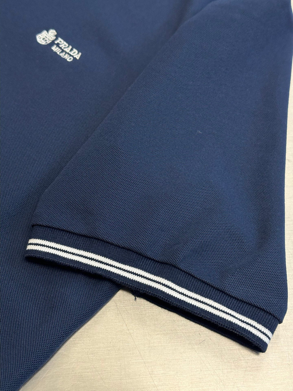 Navy polo shirt hem with contrast striped cuff band