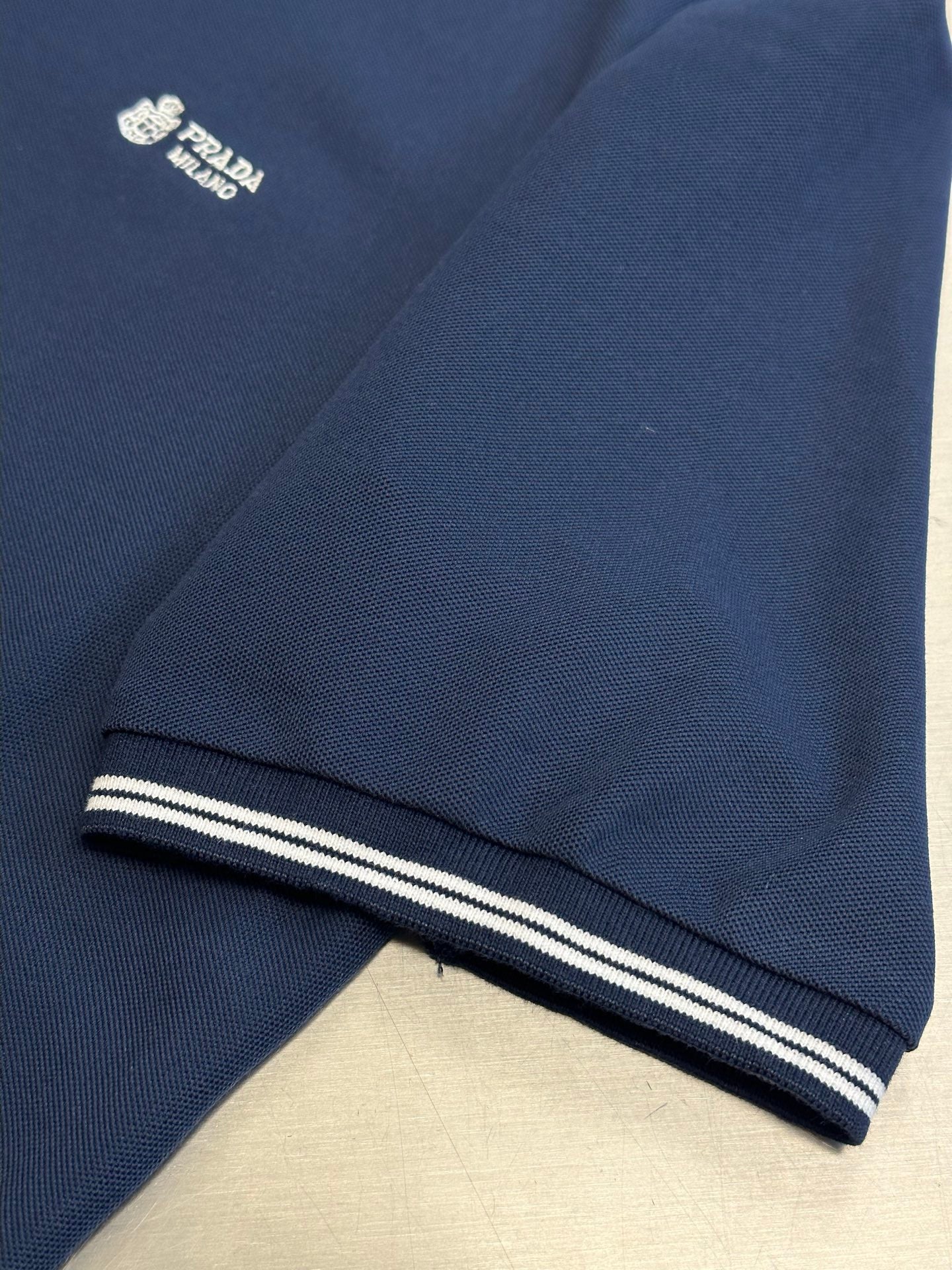 Navy polo shirt hem with contrast striped cuff band