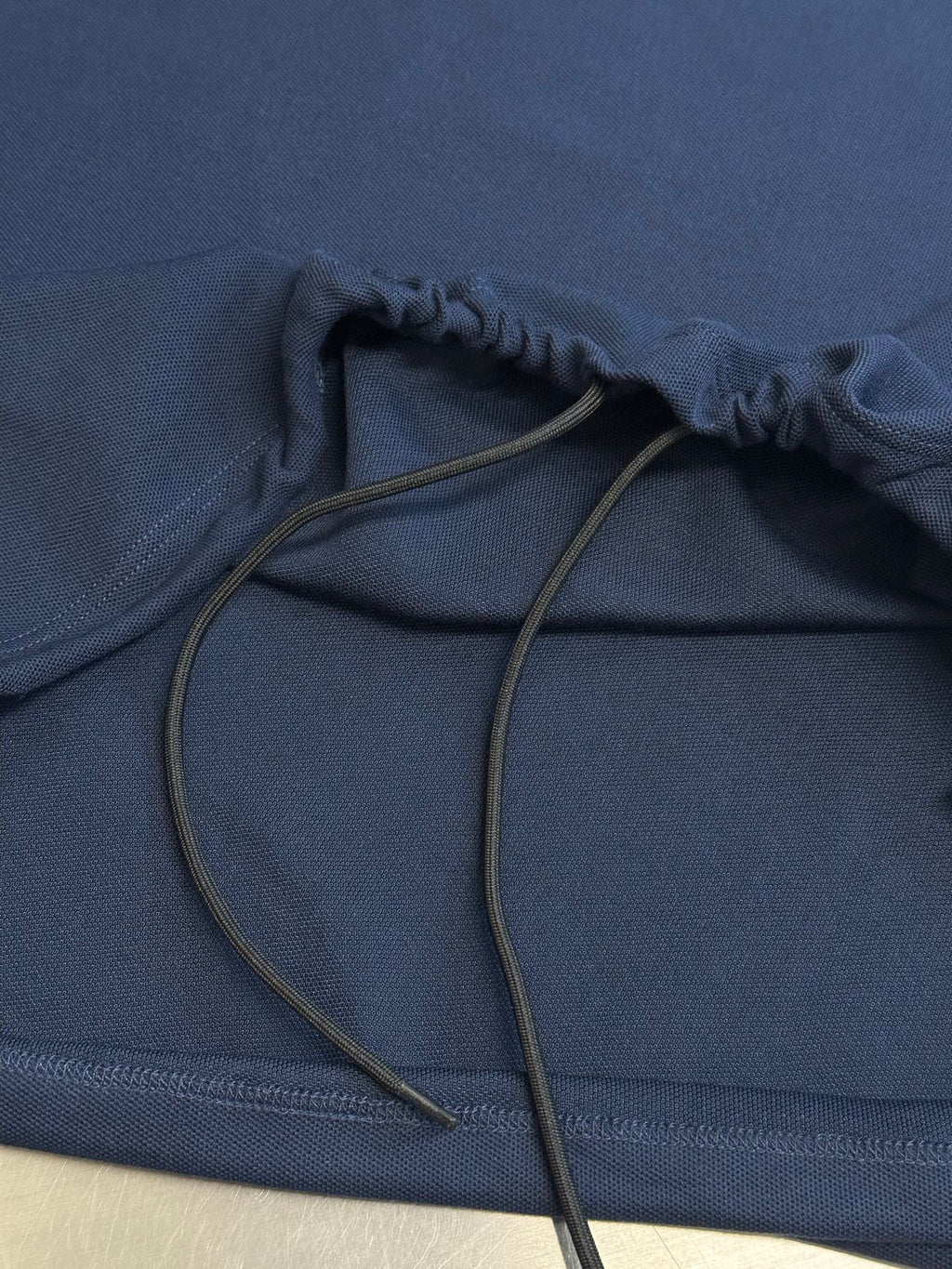 Navy polo shirt with drawstring at hem close-up