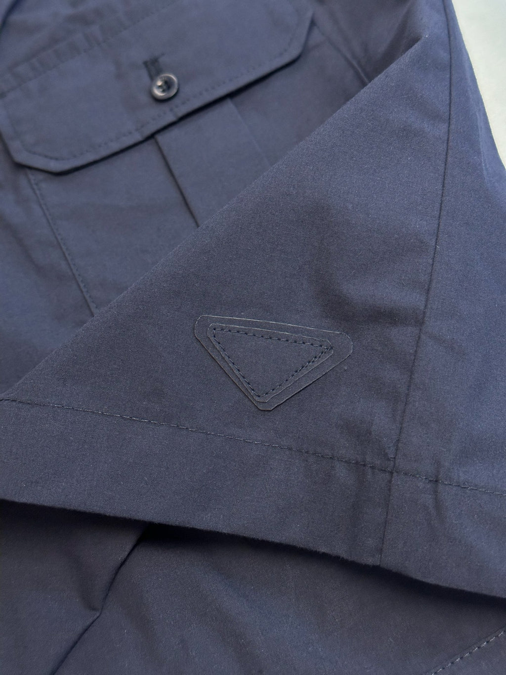 Prada navy shorts with triangular logo patch and stitched pocket seam