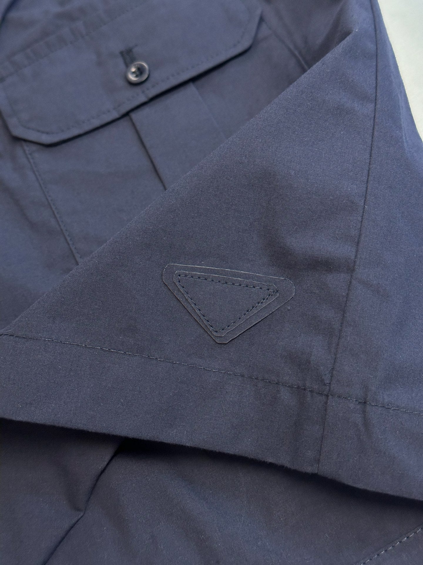 Prada navy shorts with triangular logo patch and stitched pocket seam