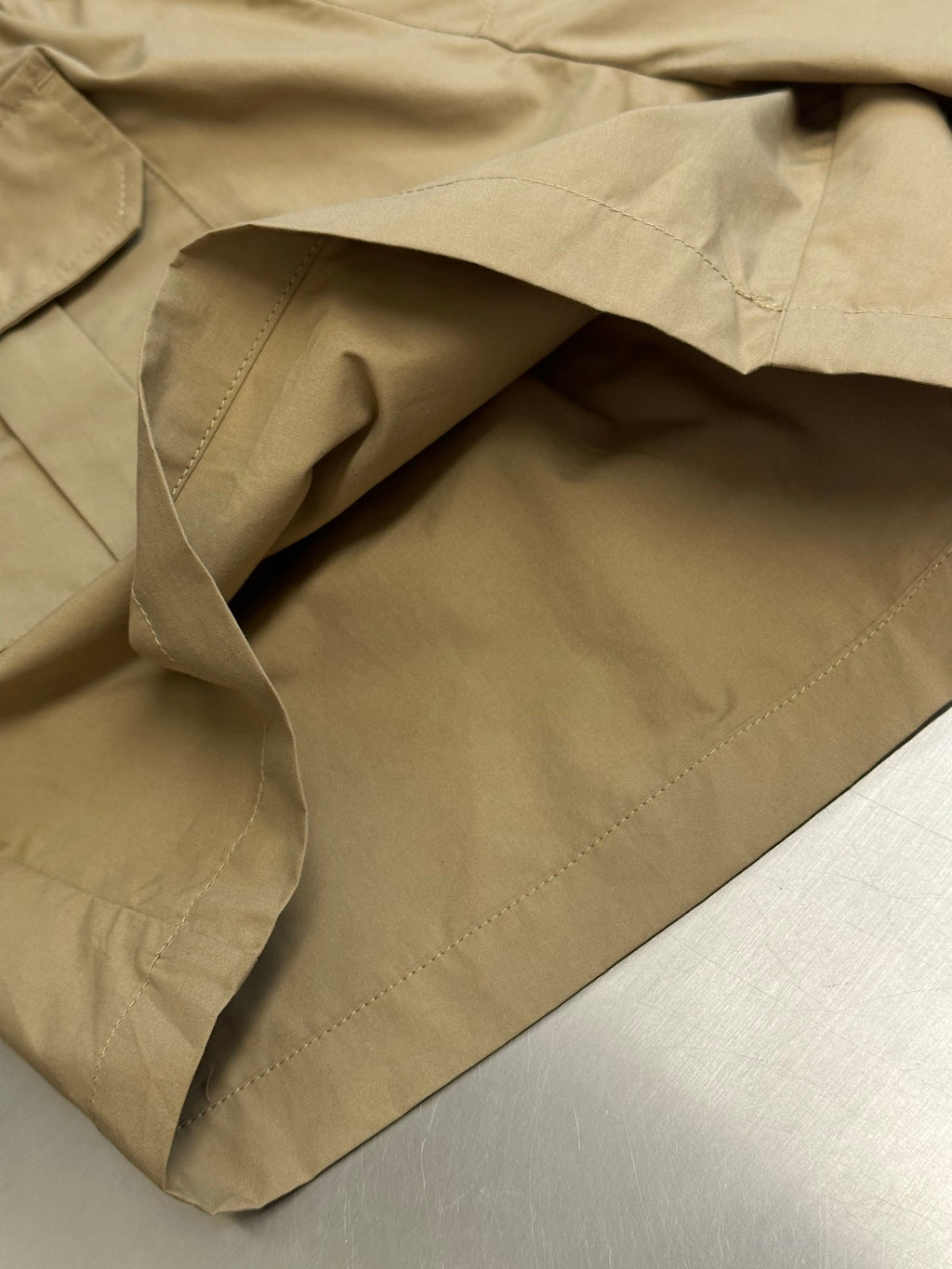 Beige cargo shorts with folded fabric and inner lining visible at the pocket area.