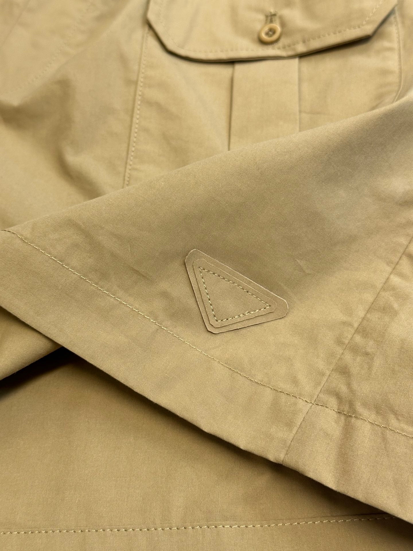 Beige cargo shorts with stitched patch detail near the hem and side seam.