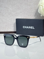 Chanel sunglasses with dark frames, dark lenses, and gold chain-style temples