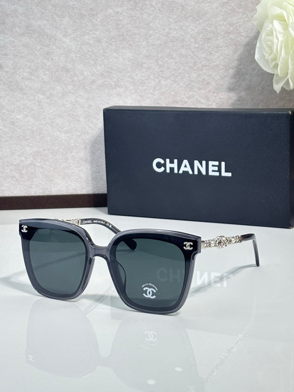 Chanel sunglasses with dark frames and dark lenses, with decorative gold temples